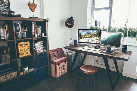 photo of two flat screen computer monitors on brown wooden table beside cube shelf inside room HD wallpaper