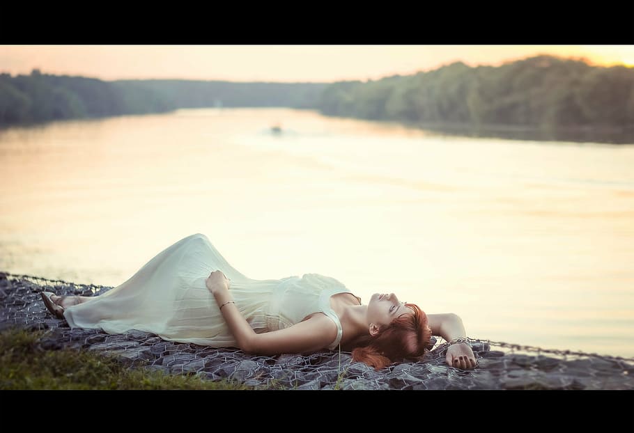 selective focus photography of woman laying on ground near body of water wearing white sleeveless long dress, HD wallpaper