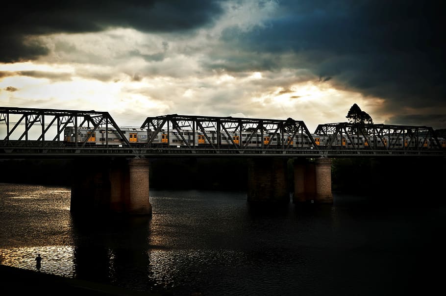 silhouette photography of bridge under nimbus clouds, gray train on bridge rail way during daytime HD wallpaper