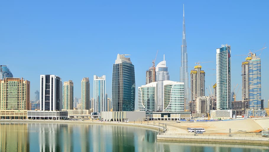 concrete building near body of water under blue sky, dubai, skyscraper, HD wallpaper