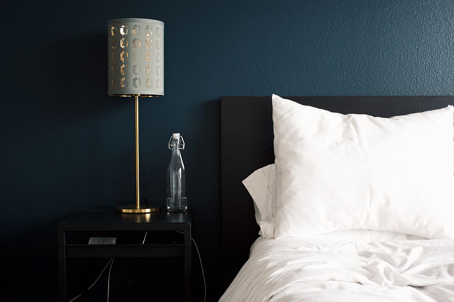 gray table lamp beside white bed pillow, silver stand with gray cone shade table lamp