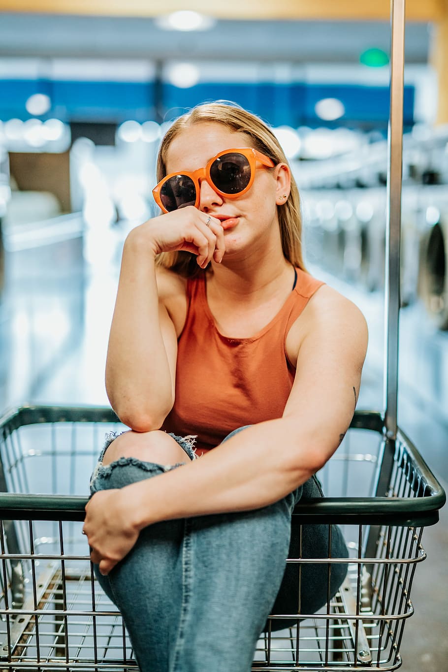 woman in brown tank top sitting on gray shopping cart, female