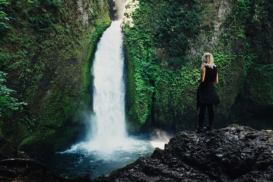 woman wearing black sleeveless dress standing in front of waterfalls HD wallpaper