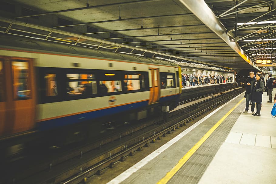man and woman standing near white, orange, and blue train, incoming HD wallpaper