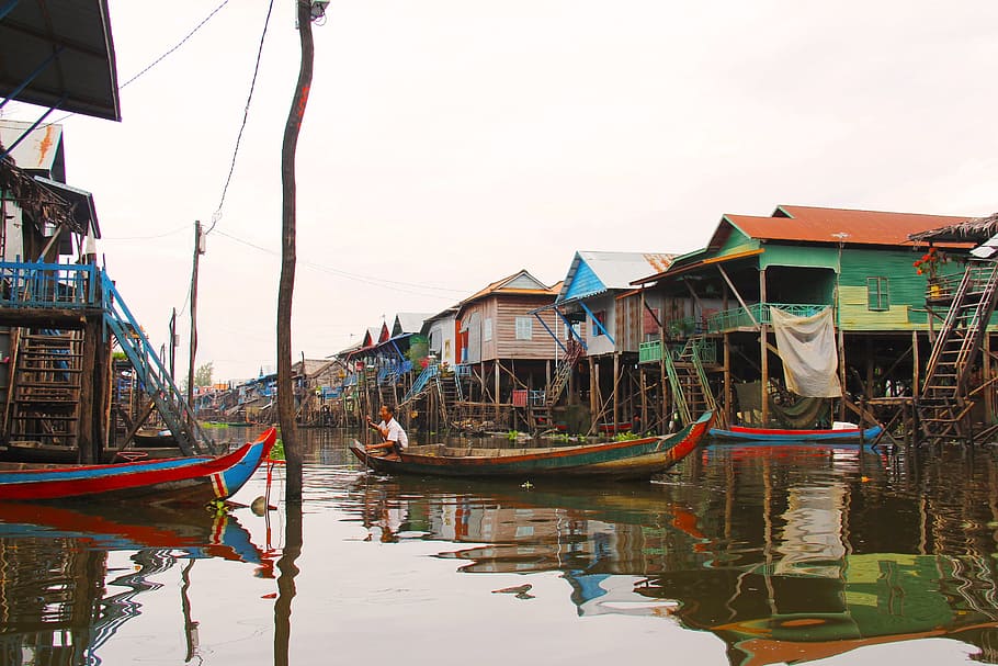 man riding on boat near houses during daytime, kompong phluk kompong