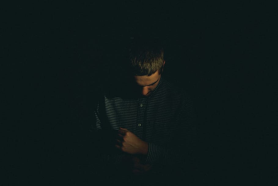 man holding his long-sleeved shirt, low light photography of man in black button-up shirt