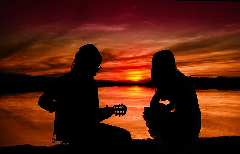 silhouette of two people sitting on ground during sunset, pair