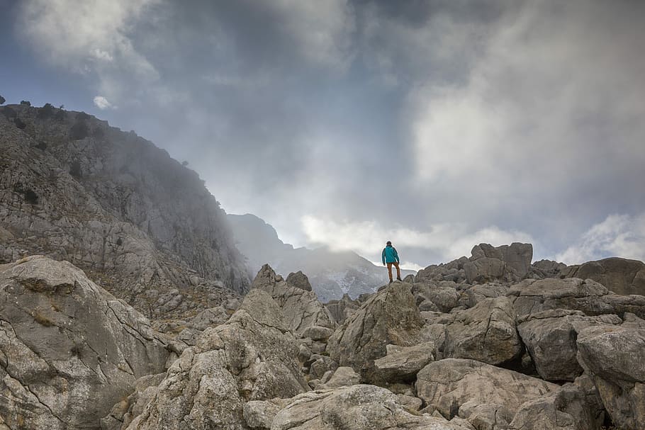 person in blue top standing on mountain during daytime, person standing on brown rocks HD wallpaper