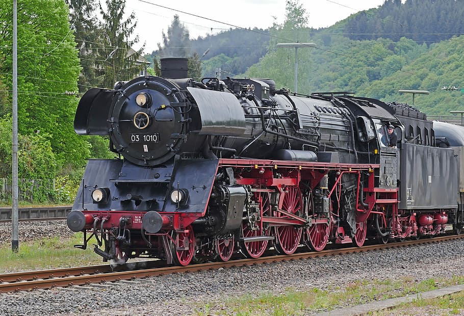 red and black train near trees during daytime, steam locomotive