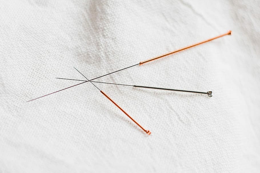 Different pokes for different folks, three assorted-color needles on white textile