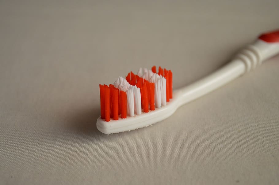 white and red toothbrush on white surface, dental care, hygiene