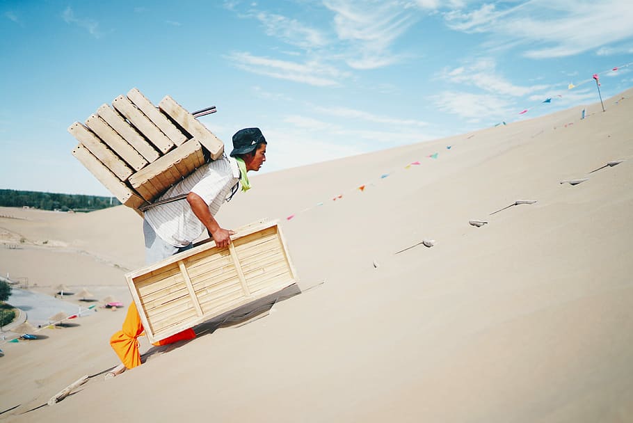 man wearing white shirt carrying brown wooden boxes, man carrying beige wooden frames HD wallpaper