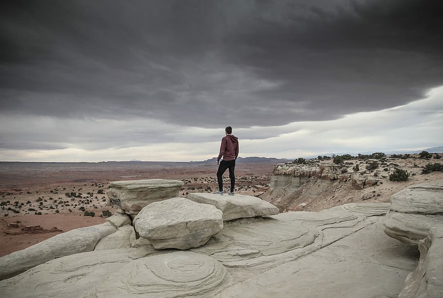 man standing on cliff looking below during daytime, person standing near cliff HD wallpaper