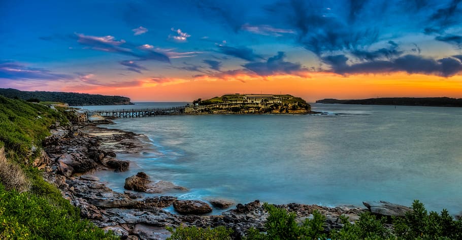 landscape photography of island, body of water near mountains HD wallpaper