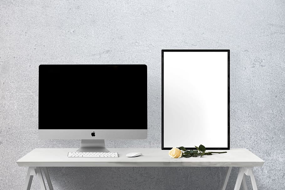 silver iMac on table beside yellow rose, mockup, wall, poster