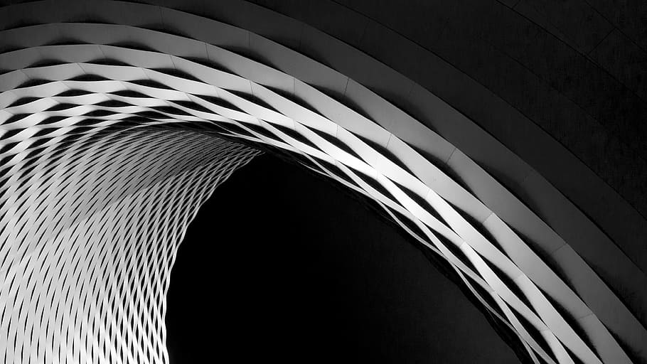 A curve in a latticework facade in black and white, lowlight photography of arch building