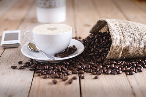 coffee beans on table, white ceramic teacup beside stainless steel spoon on white ceramic saucer HD wallpaper