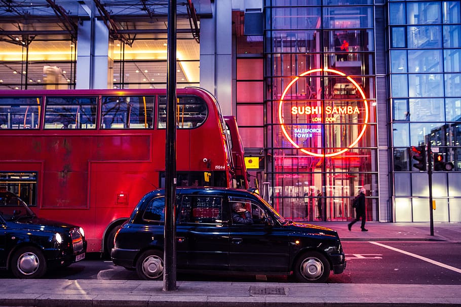 Red buses and black taxis sit on a busy London street, urban