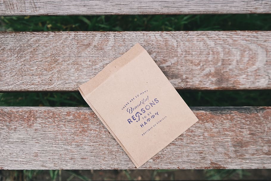 brown printing paper on brown wooden bench, Beautiful reason to be happy text