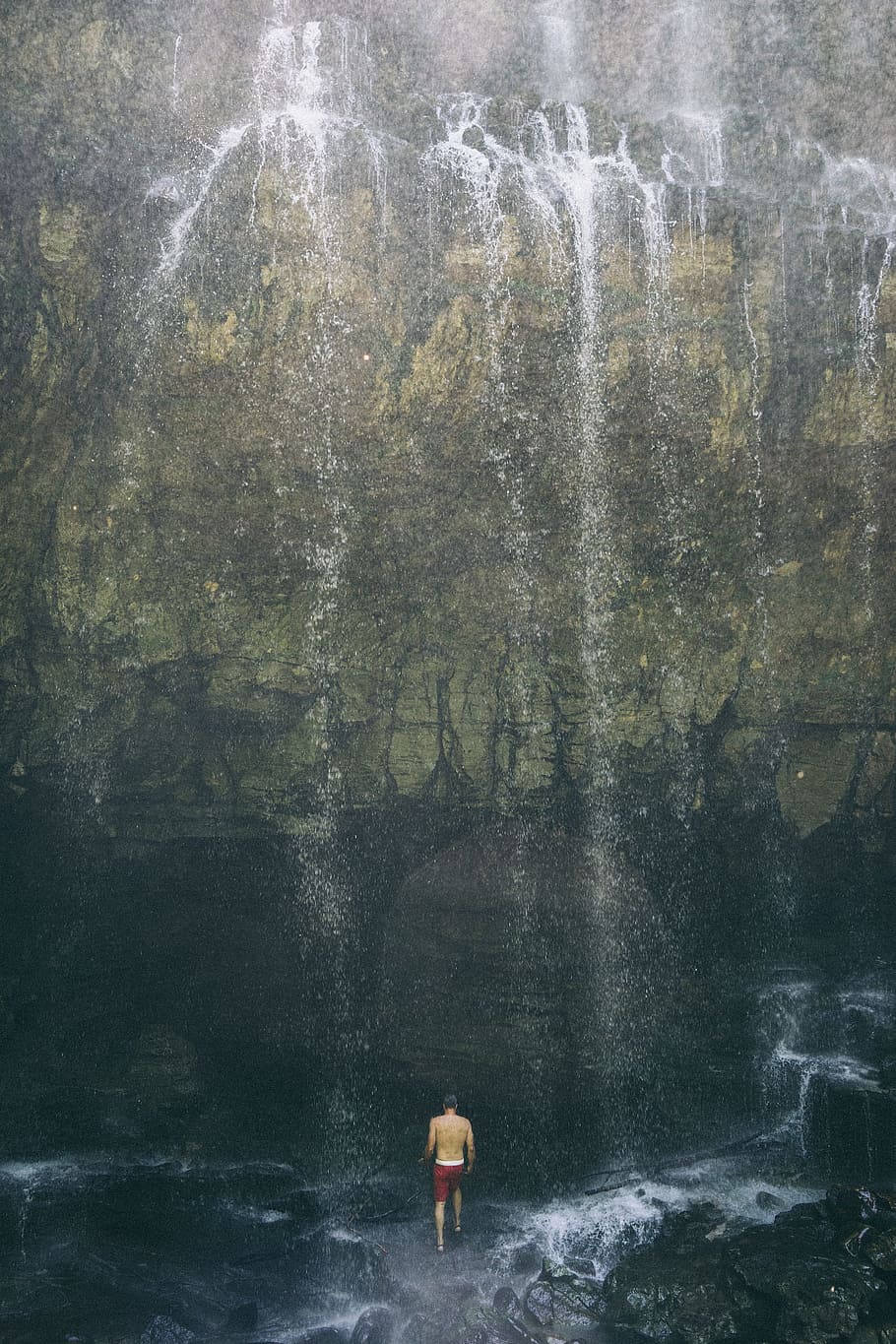 man standing underneath waterfall, man walking towards the waterfalls HD wallpaper
