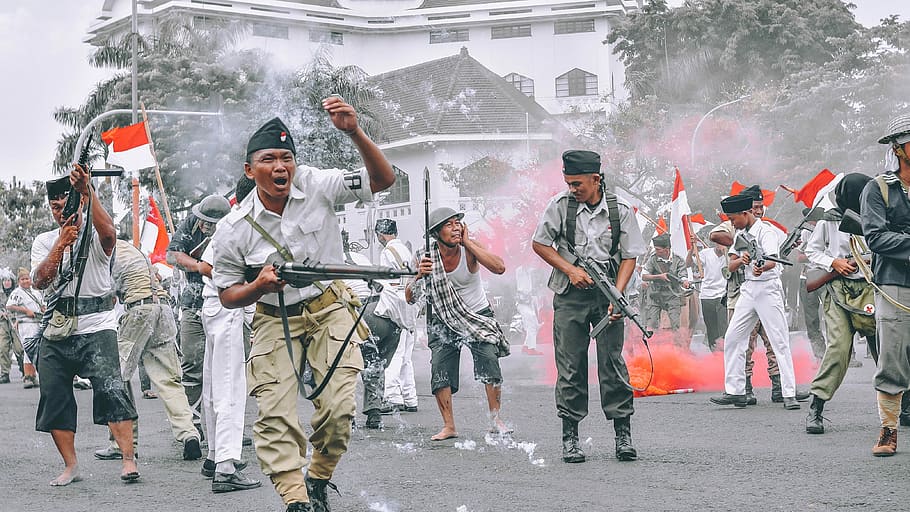 war in Indonesia, group of men holding firearms on street, man