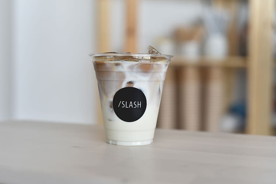 disposable cup filled with milk and ice, selective focus photo of Slash cup filled with liquid HD wallpaper