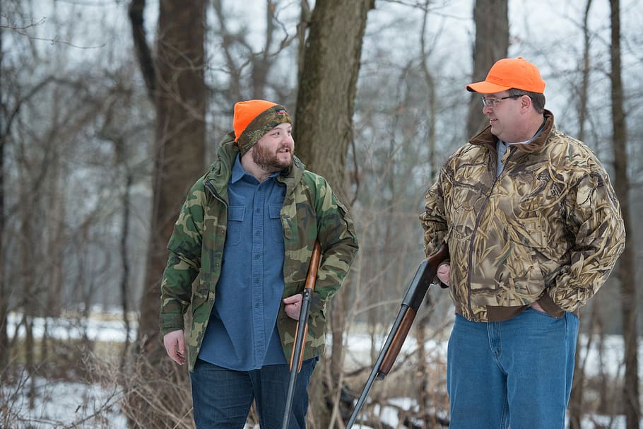 Kevin Bacon hunting, two male hunters holding hunting rifles walking in the woods