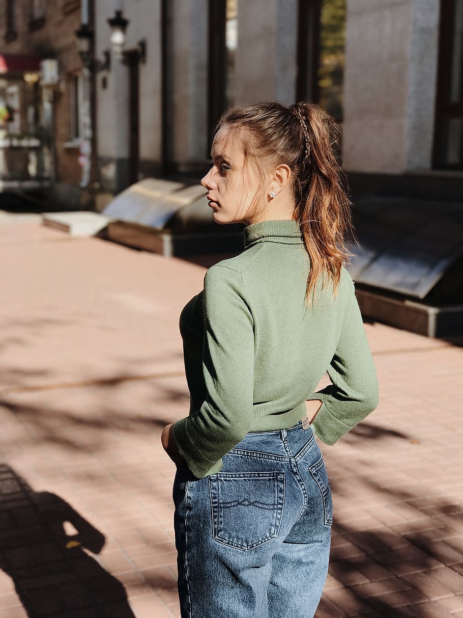 woman in green shirt and blue jeans standing near building, photo, HD wallpaper
