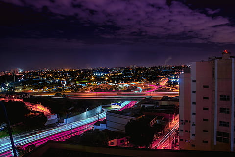 timelapse photography of vehicle passing on road under cloudy skies at night time, time lapse photography of city building during nighttime HD wallpaper