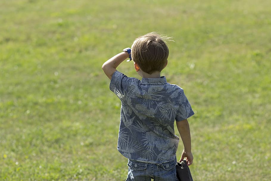 boy wearing gray and white floral short-sleeved shirt facing grass field HD wallpaper