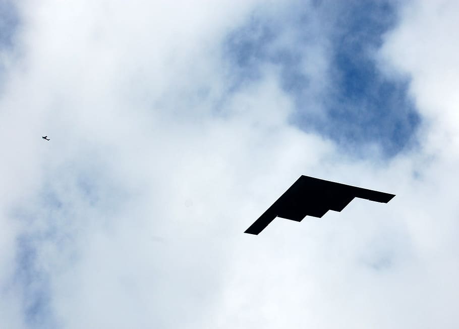 flying stealth plane during day, low angle photography of black stealth bomber flying under white skies HD wallpaper