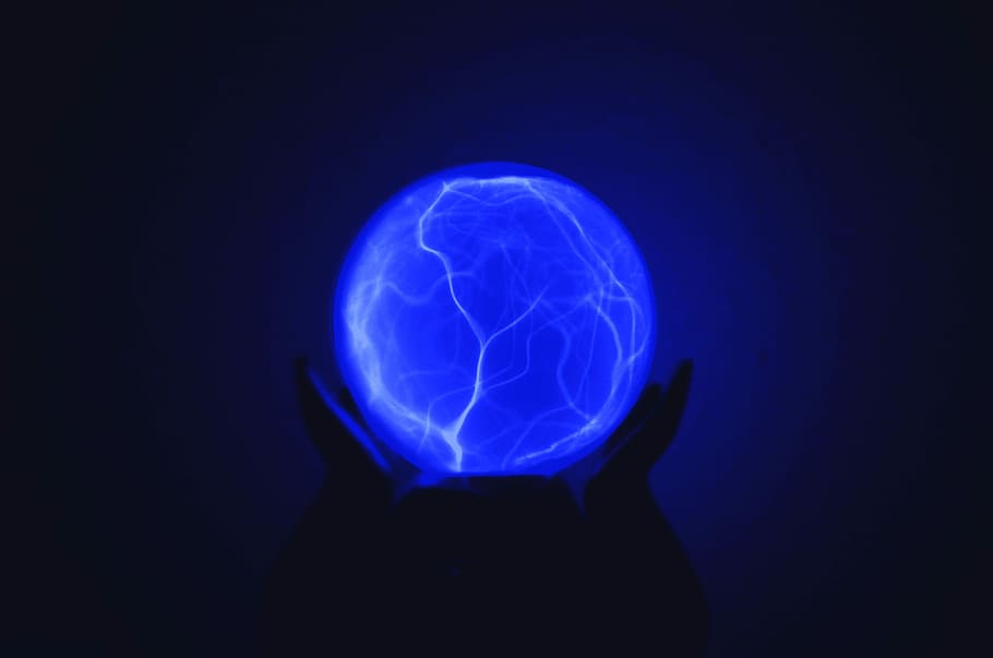 low light photo of person holding blue lighted ball, person holding plasma ball