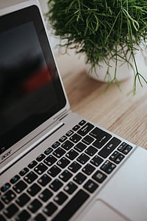 Silver Acer laptop on a wooden desk with a green plant, pencils and an Apple iPhone HD wallpaper