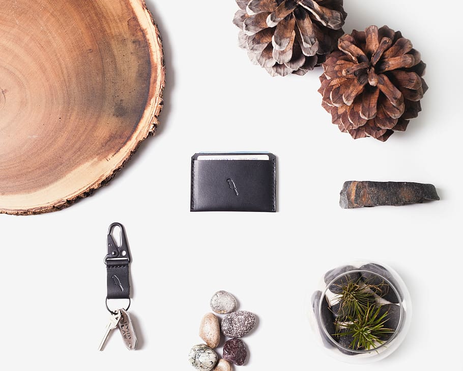 black and gray keychain near pebbles and glass fish bowl on white surface, brown wood stump HD wallpaper