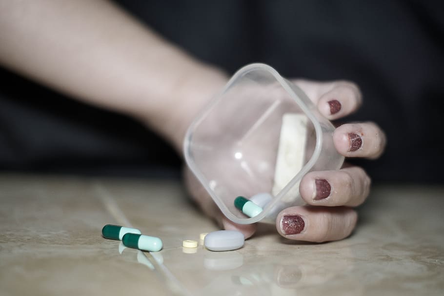 person holding square plastic container with medicines, mental health