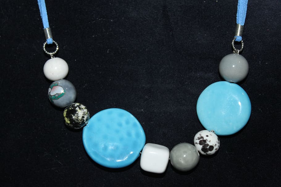 beaded teal, gray, and white pendant necklace on black surface