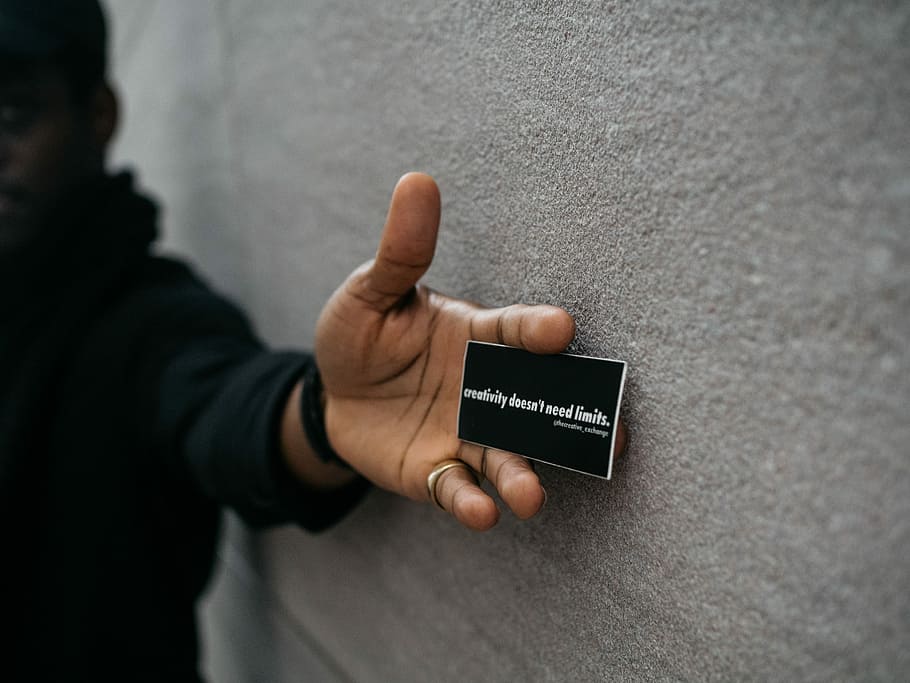 person holding black name plate, person holding white business card near wall HD wallpaper