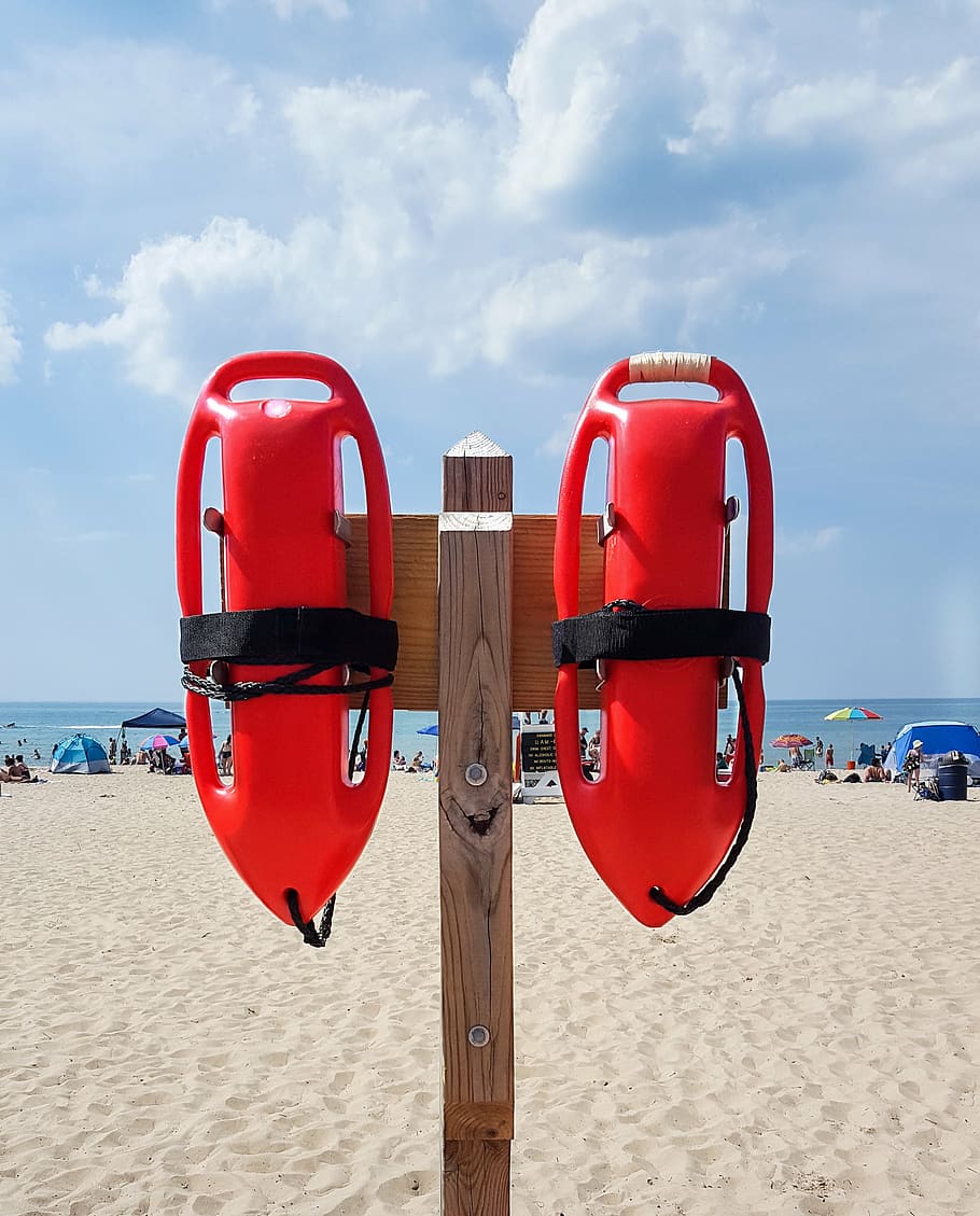 two red floaties hanging on brown wooden post, lifeguard, life guard