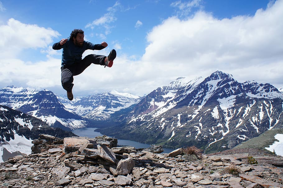 man jumping over gray stones, man jumping on top of mountain HD wallpaper