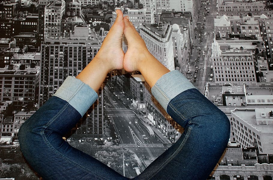 person wearing blue denim pants lying on grayscale photo of building mat HD wallpaper