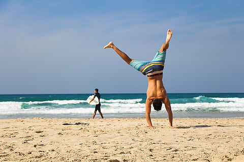 man standing using hand on seashore during daytime, handstand HD wallpaper