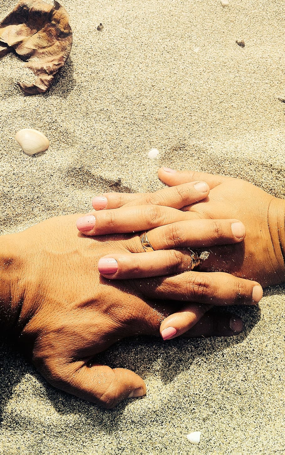 man and woman holding each others hand, man and woman's hand with rings holding each other on sand at daytime HD wallpaper