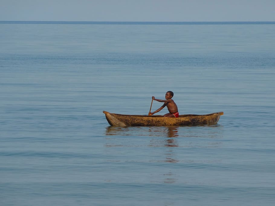 boy rowing in brown canoe, malawi, malawi lake, lake malawi, child