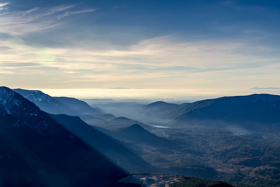 mountain covered by fogs, black mountain range near river under white skies at daytime HD wallpaper