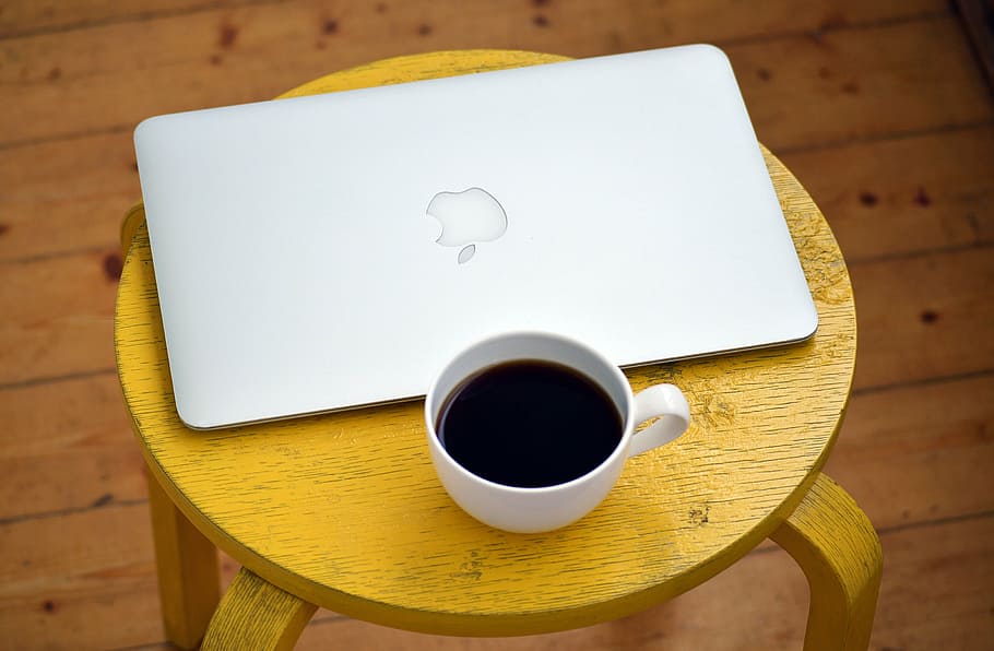 black coffee filled white cup and MacBook Air on top of brown wooden table HD wallpaper