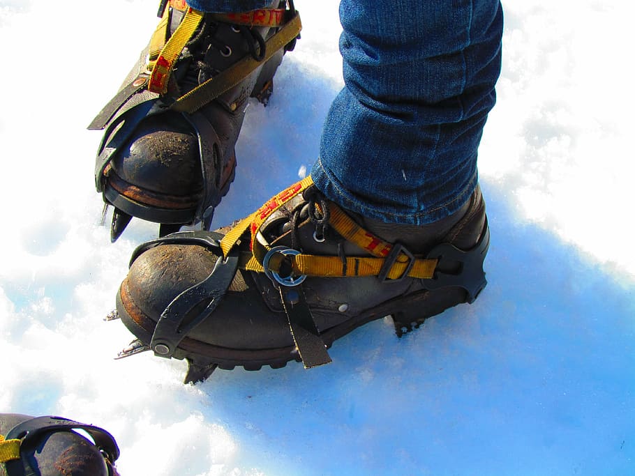 person wearing black ice boots, hiking, shoes, ice spikes, glacier