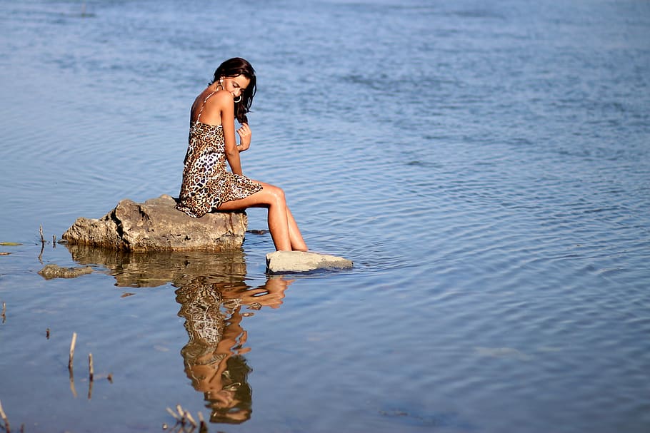 woman sitting on gray rock with feet in water, girl, wild, dress