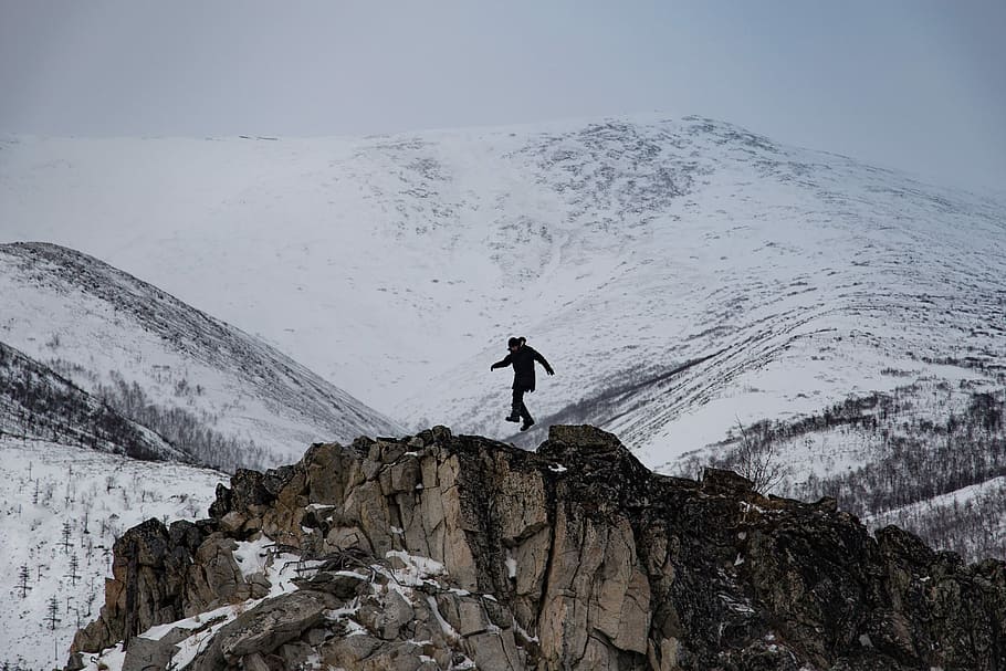 man on top of brown mountain near white mountains during daytime HD wallpaper