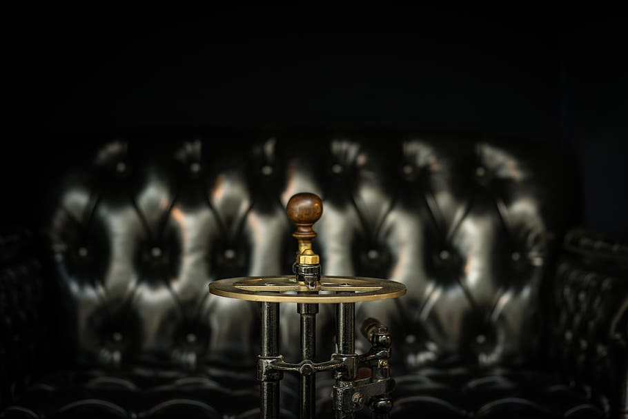 closeup photo of crank tool beside sofa, selective focus photography of steampunk lamp near tufted black sofa HD wallpaper