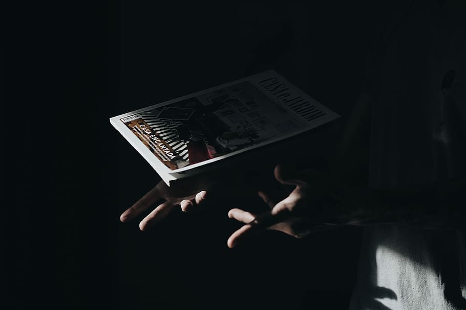 person holding book, hand, shadow, night, dark, magazine, minimal